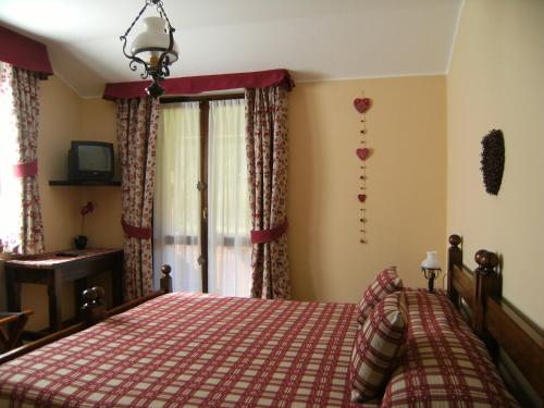 a bedroom with a bed with a red checkered blanket at Albergo Thurwieser in Santa Caterina Valfurva