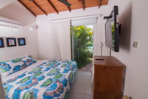 1 dormitorio con 1 cama, TV y ventana en Cabaña Coveñitas 4, en Coveñas