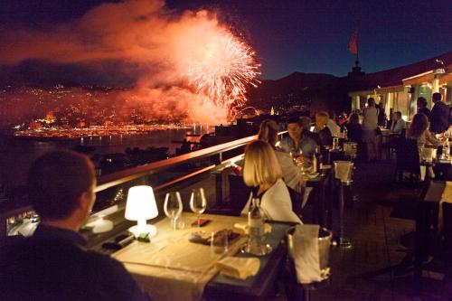a group of people sitting at a restaurant watching fireworks at Grand Hotel Bristol Resort & Spa, by R Collection Hotels in Rapallo