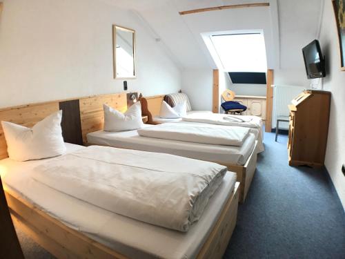 a hotel room with two beds and a tv at Akzenthaus Alpenrose Nesselwang in Nesselwang