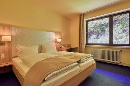 a bedroom with a large bed with a large window at Moselromantik Hotel Weissmühle in Cochem