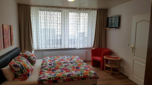 a bedroom with a bed and a red chair and a window at Haus Christiane in Cochem