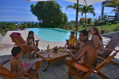 a group of people sitting around a table by a pool at Hotel Mahita Tsara in Djamandjary