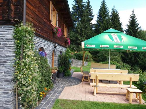 eine Terrasse mit einem grünen Sonnenschirm und einer Bank in der Unterkunft Chata U Vlastíka in Malá Morávka