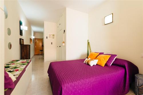 een slaapkamer met een paars bed met oranje kussens bij Al Golpito in Las Palmas de Gran Canaria
