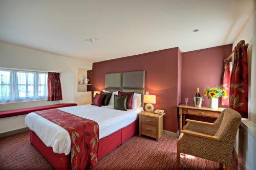 um quarto de hotel com uma cama grande e uma cadeira em The Deddington Arms em Banbury