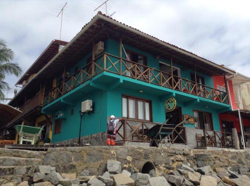 a man standing in front of a blue house at Pousada Tranquila in Morro de São Paulo