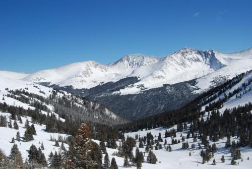 a snowy mountain range with trees and snow covered mountains at Frisco Lodge in Frisco