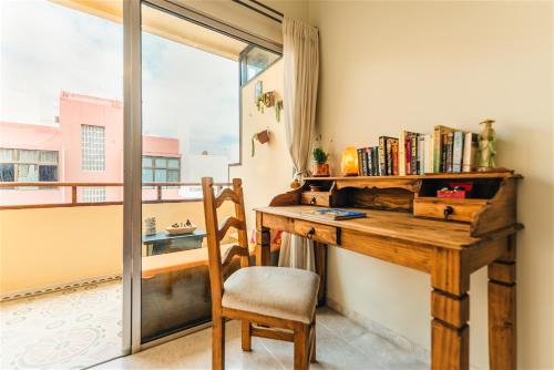 ラスパルマス・デ・グランカナリアにあるAl Golpitoの木製デスク、椅子、窓が備わる客室です。