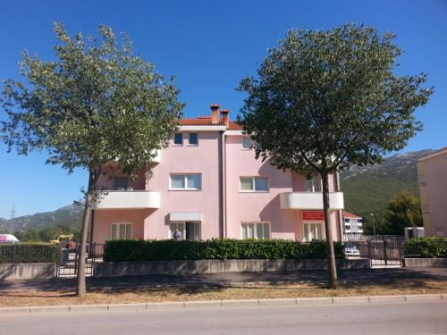 een groot roze gebouw met twee bomen ervoor bij Apartment Smodlaka in Dugopolje
