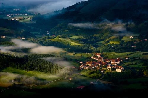 a town in a valley with fog in the mountains at Casa Rural Zigako Etxezuria in Ziga