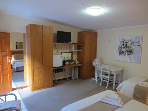 a living room with a room with a bed and a tv at Masada Guest House in Langebaan