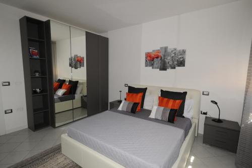 ein Schlafzimmer mit einem Bett mit orangefarbenen Kissen und einem Spiegel in der Unterkunft Sun Terrace Appartment in Lucca