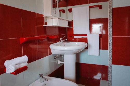 un bagno rosso e bianco con lavandino e servizi igienici di Residence Verde Mare Official Site a Tortolì