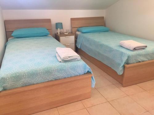 - une chambre avec 2 lits avec des draps bleus et verts dans l'établissement Suite sul mare, à Mascali