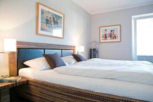 1 dormitorio con 1 cama blanca grande y 2 cuadros en la pared en Ferienwohnung Meeresrausch, en Westerland