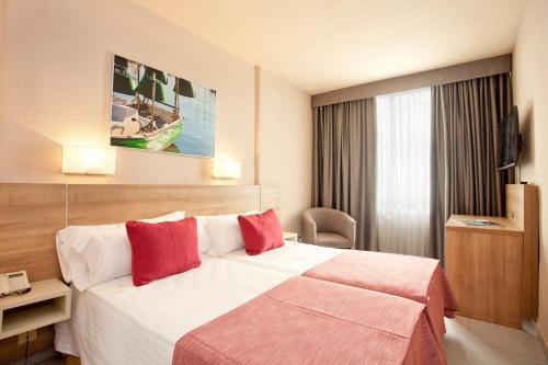 una habitación de hotel con una cama grande con almohadas rojas en Port Eugeni, en Cambrils