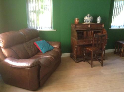 a brown leather couch in a living room with a desk at B&B Dorwyn Manor in Avebury