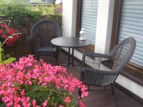 two chairs and a table on a porch with pink flowers at Pod lasem in Charzykowy