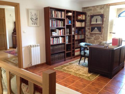 a living room with a desk and book shelves at Solar da Roseira in Capinha