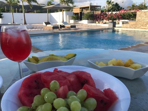 a table with a plate of fruit and a glass of wine at Malika Apartments in Westpunt