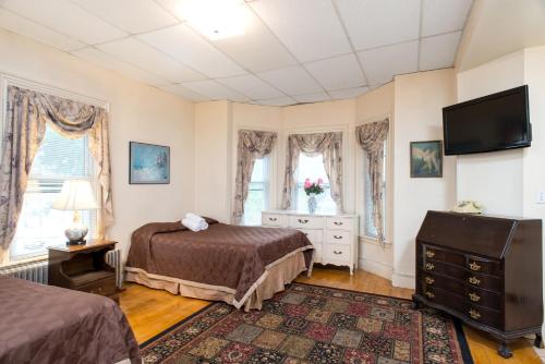 a bedroom with two beds and a flat screen tv at The Farrington Inn in Boston