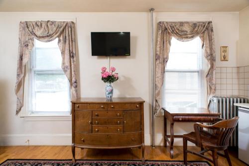 a room with a vase of flowers on a dresser with two windows at The Farrington Inn in Boston