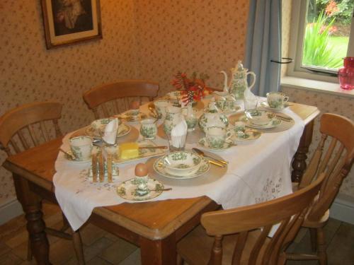 een eettafel met een wit tafelkleed erop bij THE MOATS - CODDINGTON A small private thatched cottage B&B located in quiet countryside between Ledbury and Malvern - convenient for the Malvern Three Counties Showground and 5 miles from excellent shops restaurants and Ledbury Poetry Festival in Ledbury