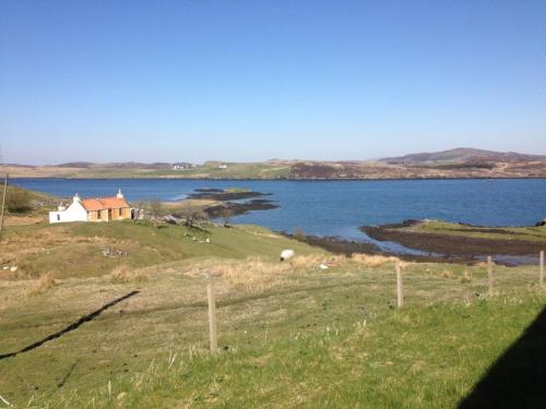 a house on a hill next to a body of water at 7 Habost in Balallan