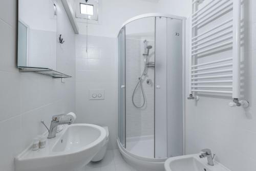 uma casa de banho branca com um chuveiro e um lavatório. em Cornelia Penthouse em Roma