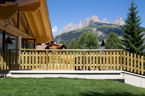 a wooden fence in front of a house with mountains at Residence Cirelle Suite & Spa in Canazei