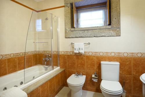 a bathroom with a toilet and a shower and a sink at Casa da Torre in Pico