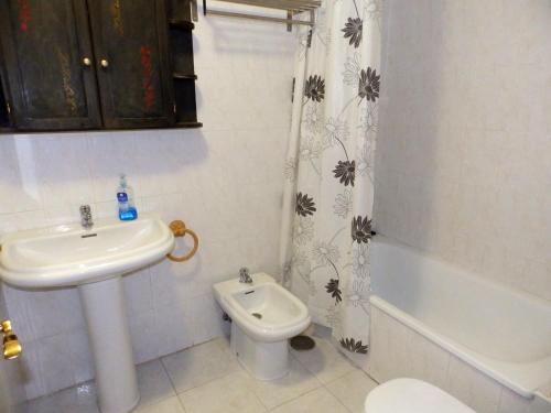 Un baño con lavabo, inodoro y cortina de ducha. en Apartamentos Medano - Mirazul 2, en El Médano
