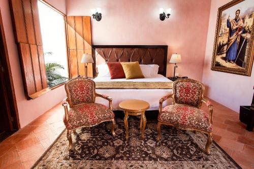 a bedroom with a bed with two chairs and a table at Hotel Doña Manuela in Mompos