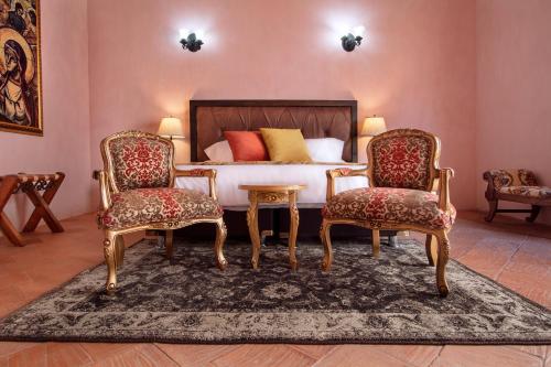 a bedroom with a bed and two chairs at Hotel Doña Manuela in Mompos