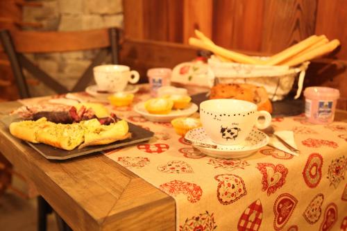 stół z tkaniną stołową z jedzeniem i kubkami w obiekcie Mi Casa Tu Casa w mieście Brusson