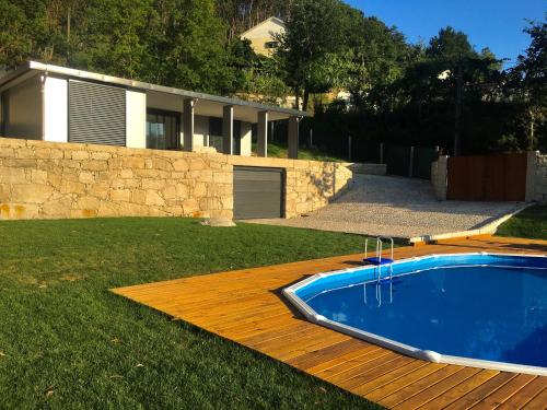 a swimming pool on a wooden deck next to a house at The Green Roof House in Vieira do Minho