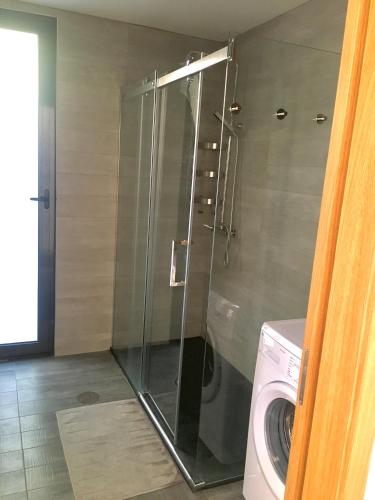 a glass shower in a bathroom with a washing machine at The Green Roof House in Vieira do Minho