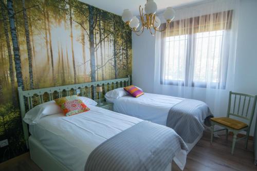 2 Betten in einem Zimmer mit Bäumen an der Wand in der Unterkunft El Jardin de Manuela in Santibáñez del Val