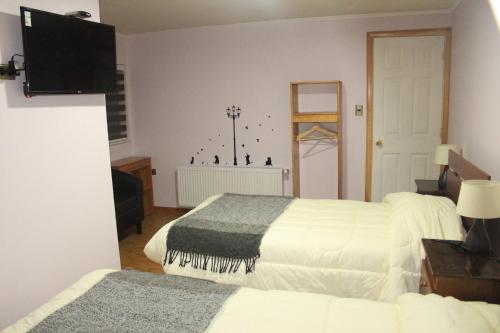 a hotel room with two beds and a television at Hostal Los Teros in Coihaique