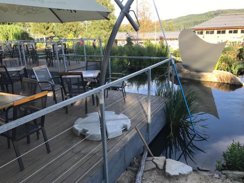 a deck with tables and chairs and a pond at Apartmány Pinie Lipno in Lipno nad Vltavou