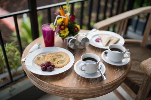 een tafel met twee kopjes koffie en borden eten bij Pecatu Ubud Guest House in Ubud