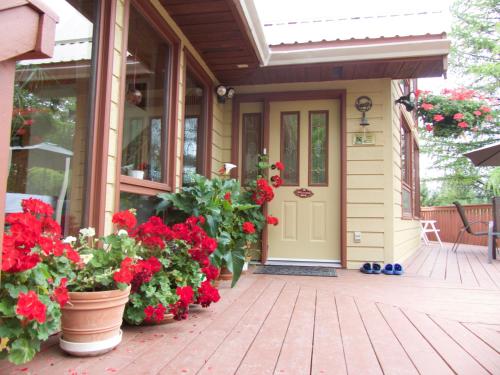 a porch of a house with red flowers on it at End of the road B & B in Cranbrook