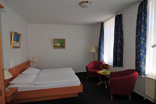 ein Hotelzimmer mit einem Bett und zwei Stühlen in der Unterkunft Hotel Stadt Reinfeld in Reinfeld