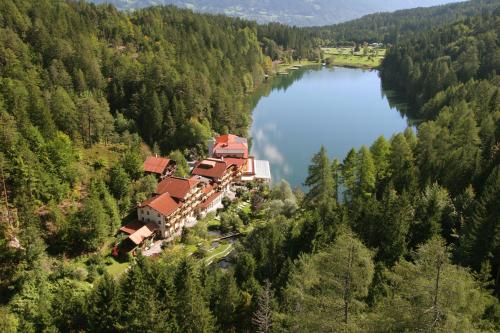 an aerial view of a house on a hill next to a lake at Parkhotel Tristachersee in Lienz