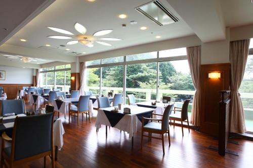 a restaurant with tables and chairs and a large window at Kagetsuen in Hakone