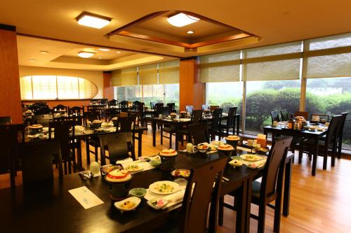 a dining room with tables and chairs and a large window at Kagetsuen in Hakone