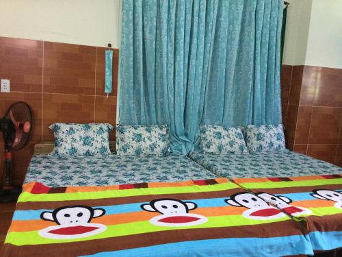 a bed with a blanket with monkey faces on it at Nhu Y Guesthouse in Phan Rang–Tháp Chàm