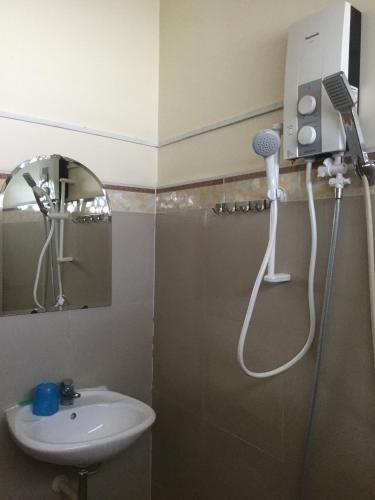 ein Bad mit einer Dusche, einem Waschbecken und einem Spiegel in der Unterkunft Nhu Y Guesthouse in Phan Rang