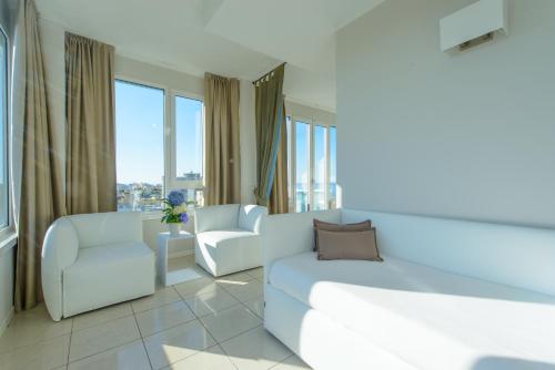 a living room with a couch and chairs and windows at Hotel Cristallo in Riccione